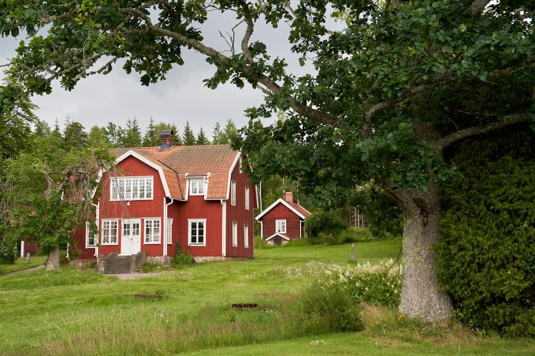 Större röd träbyggnad i sommarlandskap — exempel på en typisk dalsländsk fasad